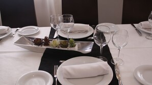 Une table à manger dressée avec de l’argenterie, des assiettes blanches et des verres à vin, agrémentée d’un chemin de table noir et d’un plateau en argent sur lequel sont disposées des plantes succulentes.