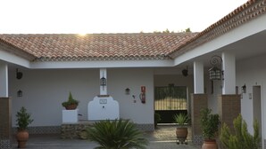 Une cour avec un toit en tuiles, des plantes en pot et un bâtiment blanc doté d’une porte et de fenêtres.