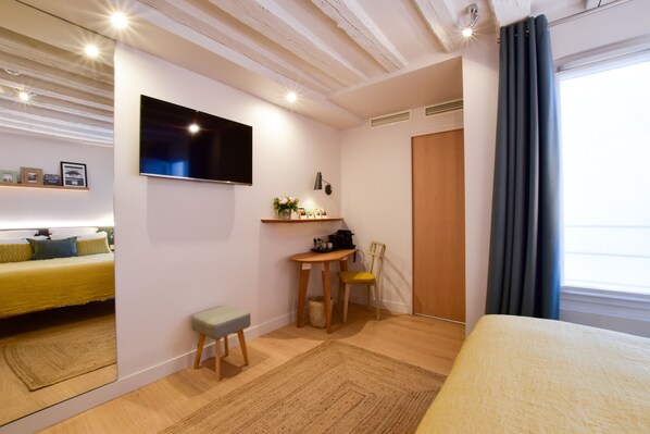 Una habitación de hotel con una cama, un escritorio con silla, un televisor y una ventana con cortinas.