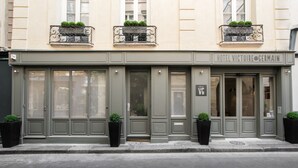 En bygning med et skilt, der viser "HOTEL VICTOIRE GERMAIN", og en stor indgangsdør.