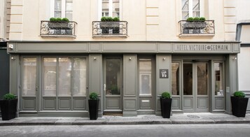 Un edificio con un letrero que dice "HOTEL VICTOIRE GERMAIN" y una puerta de entrada grande.