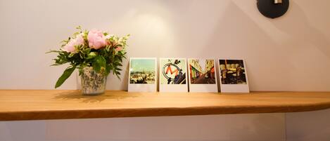 A desk with a vase of flowers, a lamp, and three framed photographs on a wooden shelf.