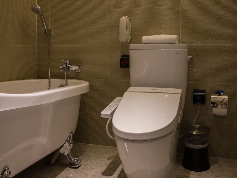 Uma casa de banho moderna com banheira, sanita e um cesto de lixo.