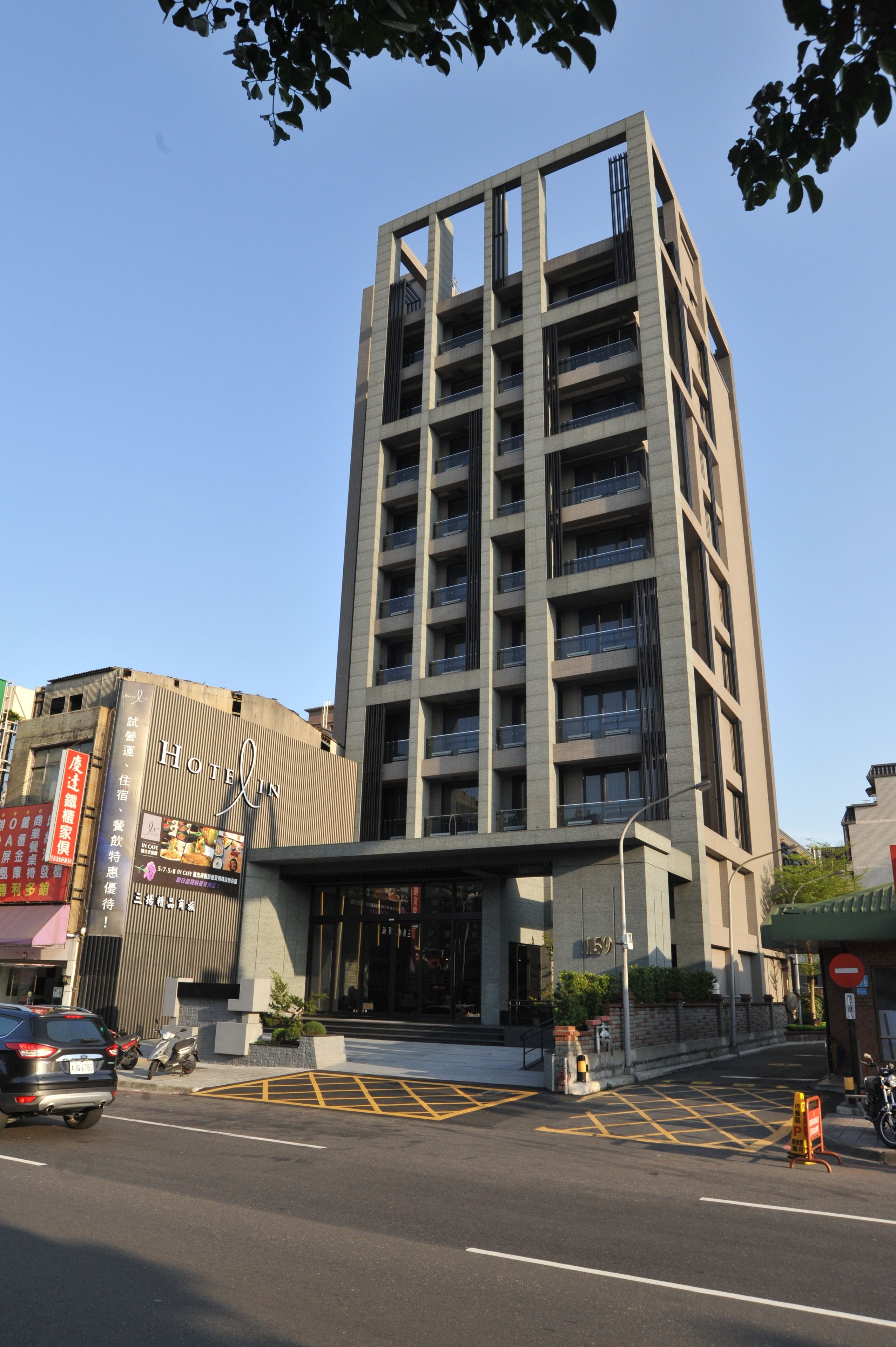 Un hotel moderno con una entrada destacada, varios pisos y un cielo despejado.