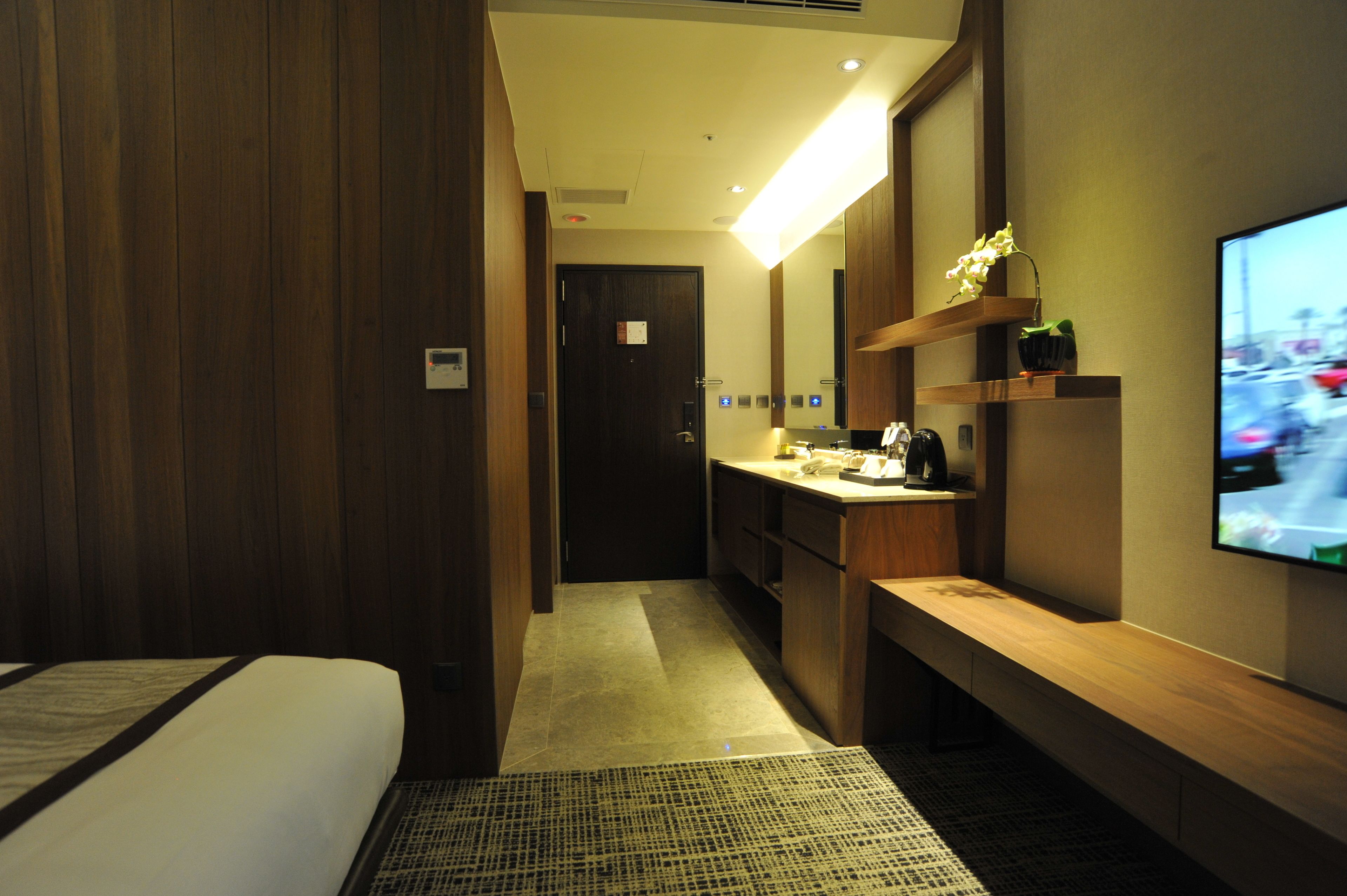 Een hotelkamer met een bed, een bureau, een televisie en een deur naar de badkamer.