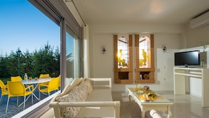 A modern living room with a sofa, a dining table with yellow chairs, a TV, and a fireplace.