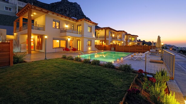 A modern multi-story house with a swimming pool, outdoor seating, and a mountain backdrop.