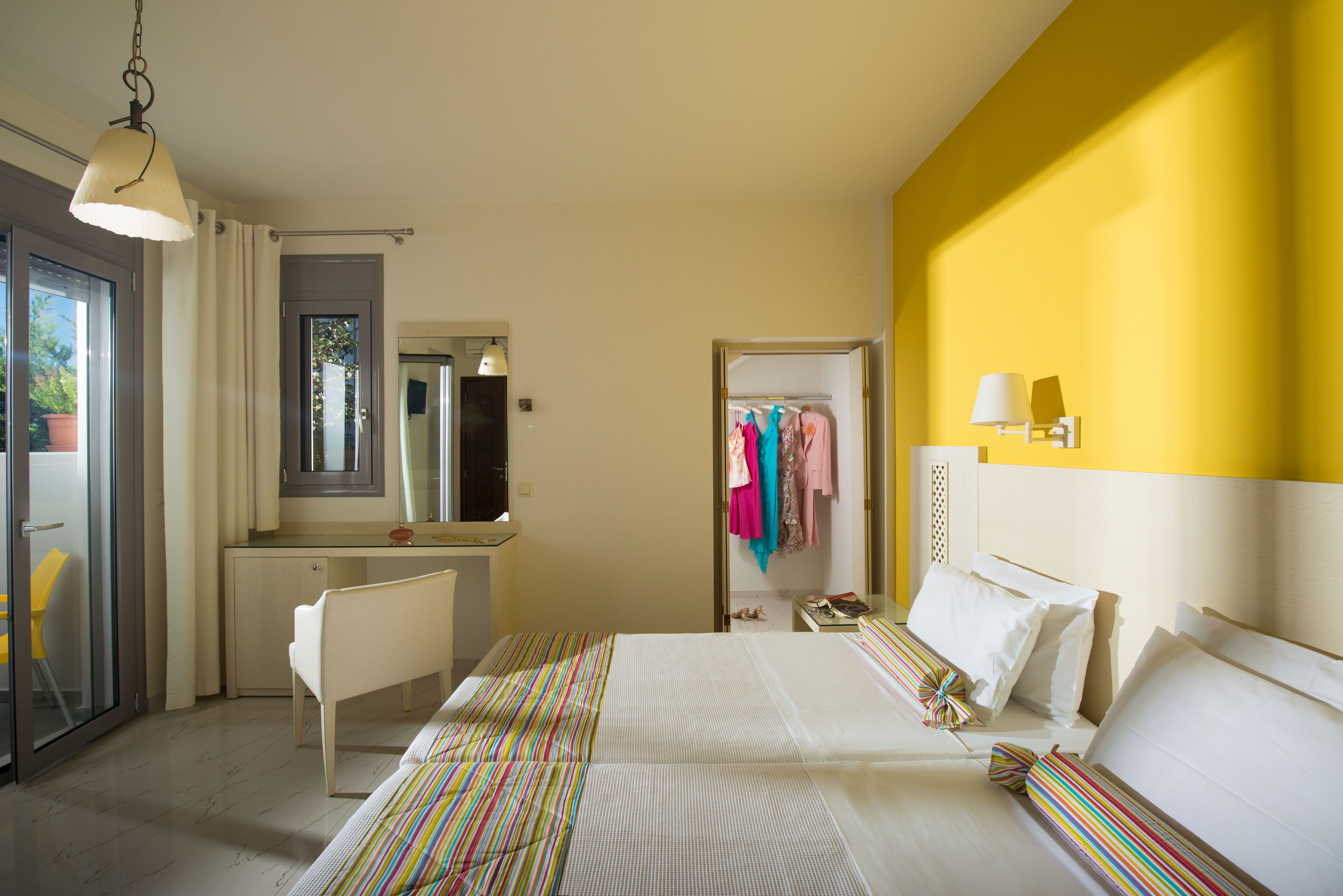 Een hotelkamer met een bed, een bureau, een stoel, een spiegel en een kledingkast.