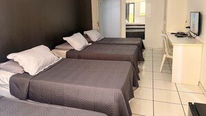 A hotel room with three beds, a desk, a television, and a door leading to another room. - Stratus Centro Hotel (Volta Redonda)