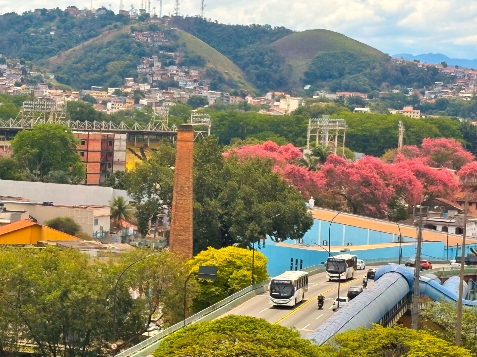 A cityscape with a prominent bridge, a bus station, and a hill with buildings.