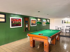 A pool table with a green felt surface, surrounded by green walls and framed pictures. - Stratus Centro Hotel (Volta Redonda)