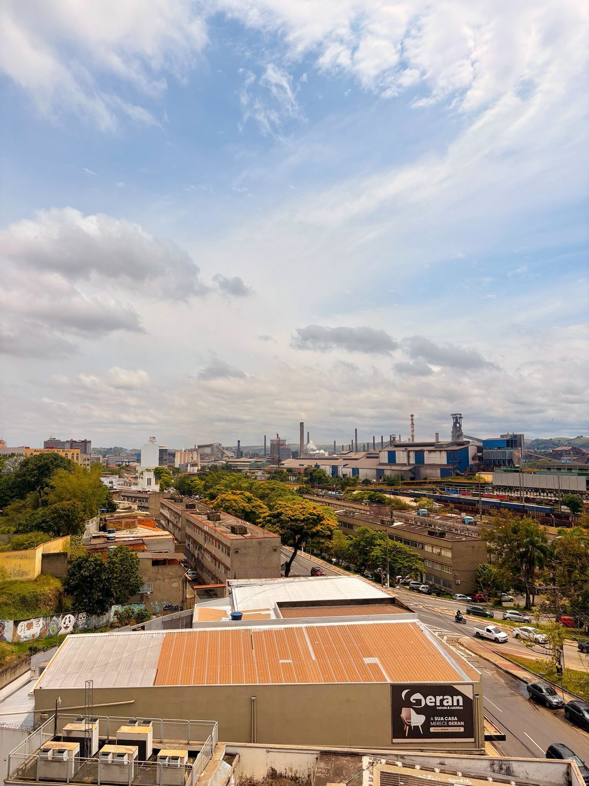 Un paisaje urbano con edificios industriales, un gran cartel publicitario y cielo despejado.