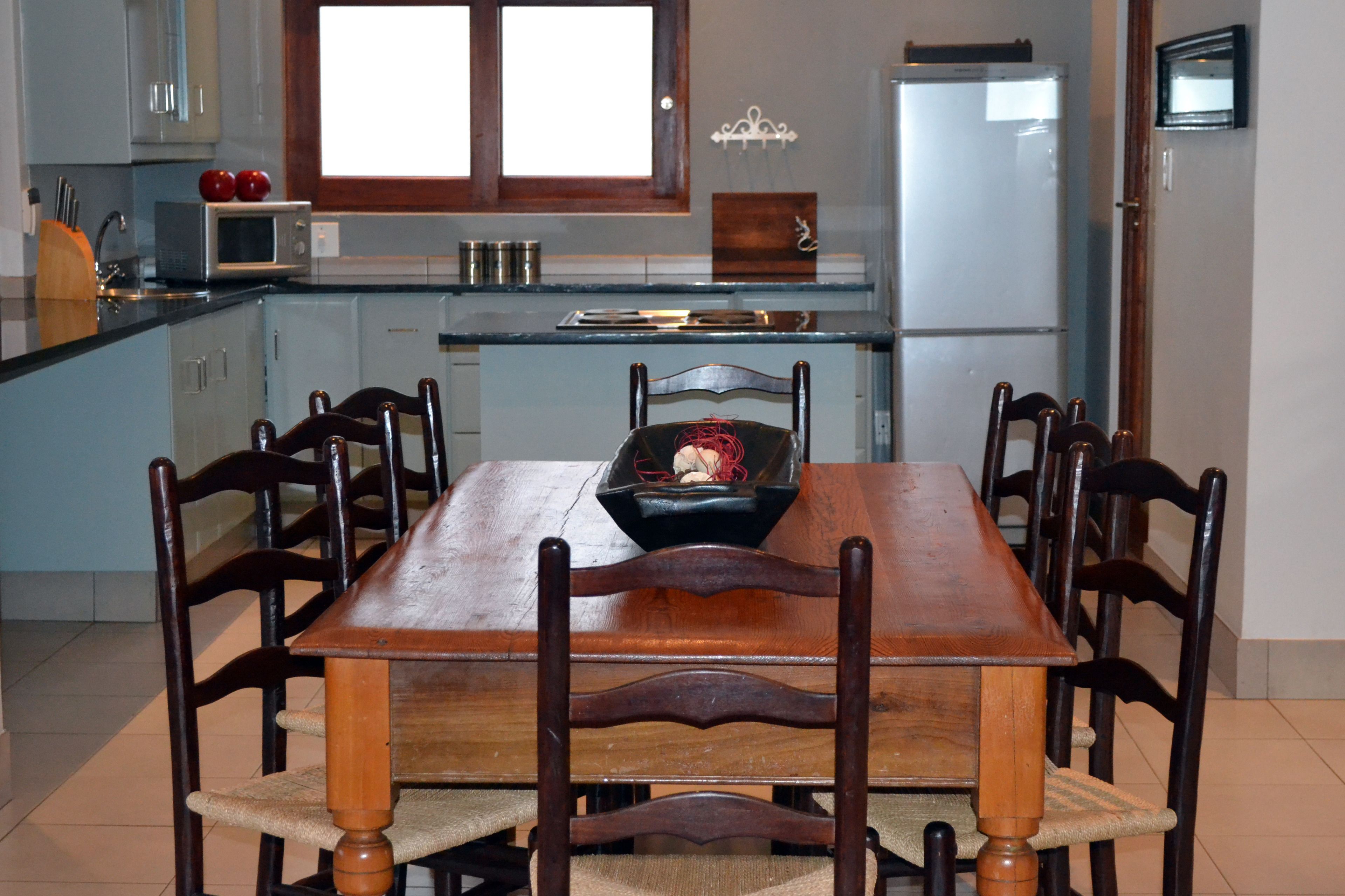 Un coin repas avec une table et des chaises en bois, un four à micro-ondes et un réfrigérateur.
