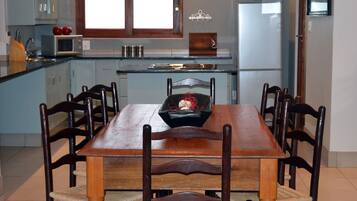 Un coin repas avec une table et des chaises en bois, un four à micro-ondes et un réfrigérateur.