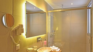 A modern bathroom with a large mirror, a sink with a bowl, a handheld showerhead, and a glass-enclosed shower. - Elia Kentron- Adults Only (Chania)