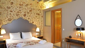 A bedroom with a stone wall, a wooden headboard, a bed with white linens, two bedside lamps, and a small table with a lamp. - Elia Kentron- Adults Only (Chania)