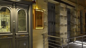 A hotel entrance with a sign reading "ENIA KENTRON," a metal gate, and a stone wall with shutters. - Elia Kentron- Adults Only (Chania)
