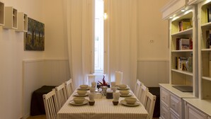 A dining area with a table set for six, surrounded by chairs, with a bookshelf and a painting on the wall. - Sui Tetti di Napoli (Naples)