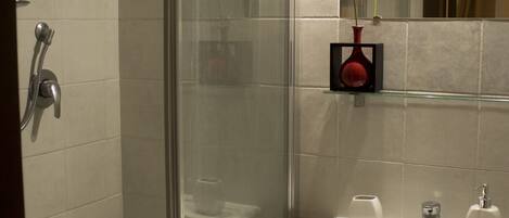 A modern bathroom with a glass-enclosed shower, a white sink, and a mirror above it.