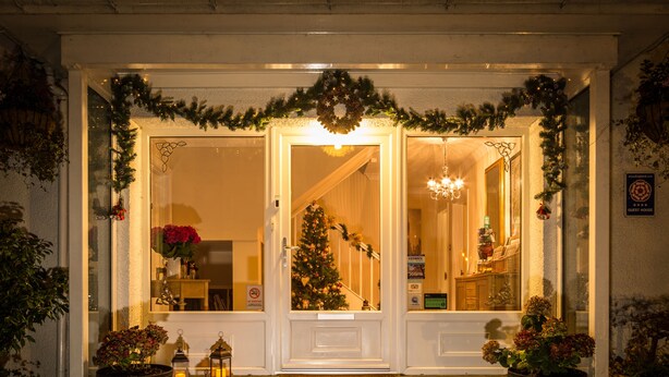 A hotel entrance with a Christmas tree, potted plants, and a lit welcome mat. - Hermiston Guest House (Keswick)