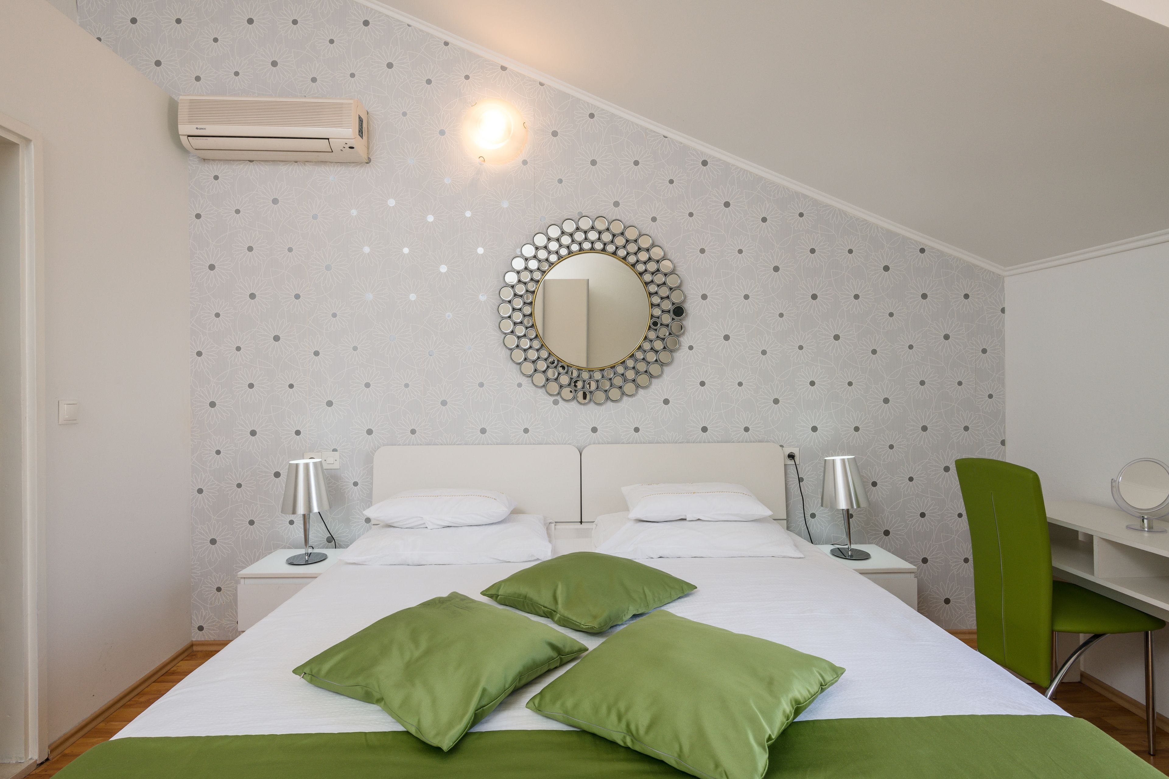 Une chambre à coucher bien rangée, avec un lit, deux tables de chevet, un miroir et un bureau.