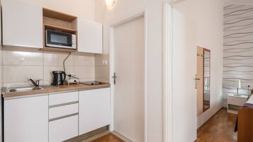 Una cocina compacta con microondas, lavamanos y encimera de madera.