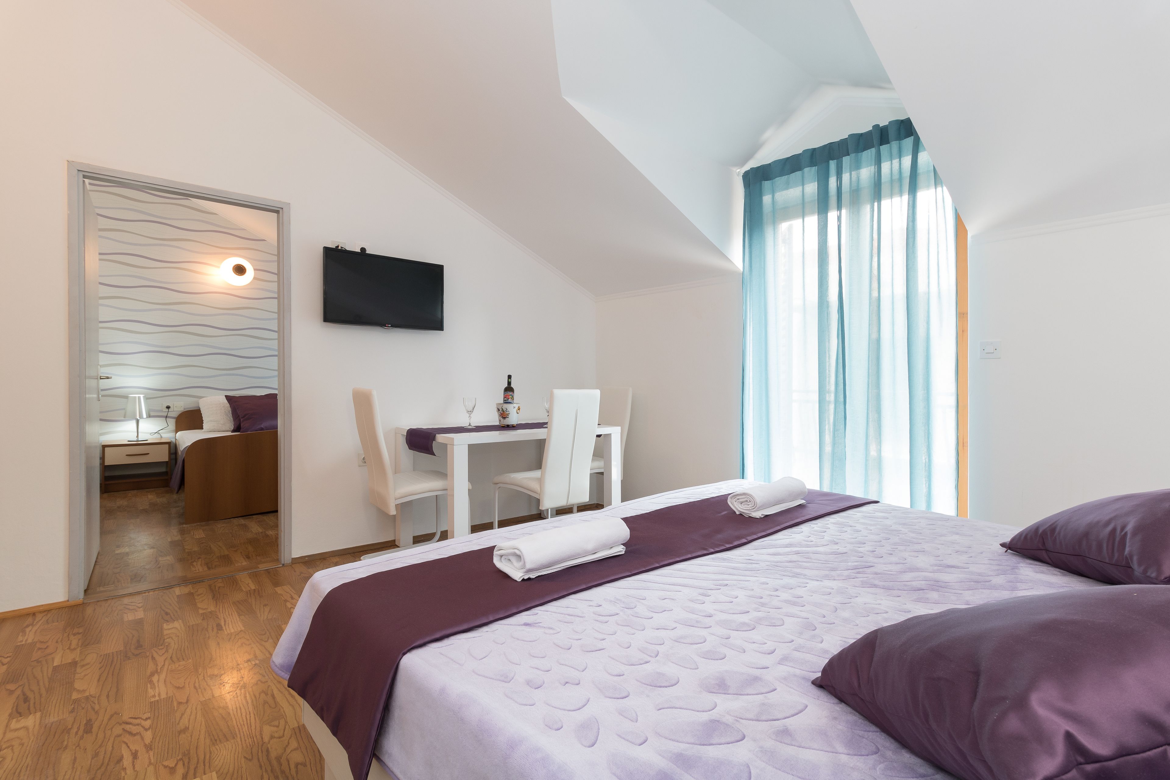 A modern hotel room with a large bed, a desk, and a view of the city.