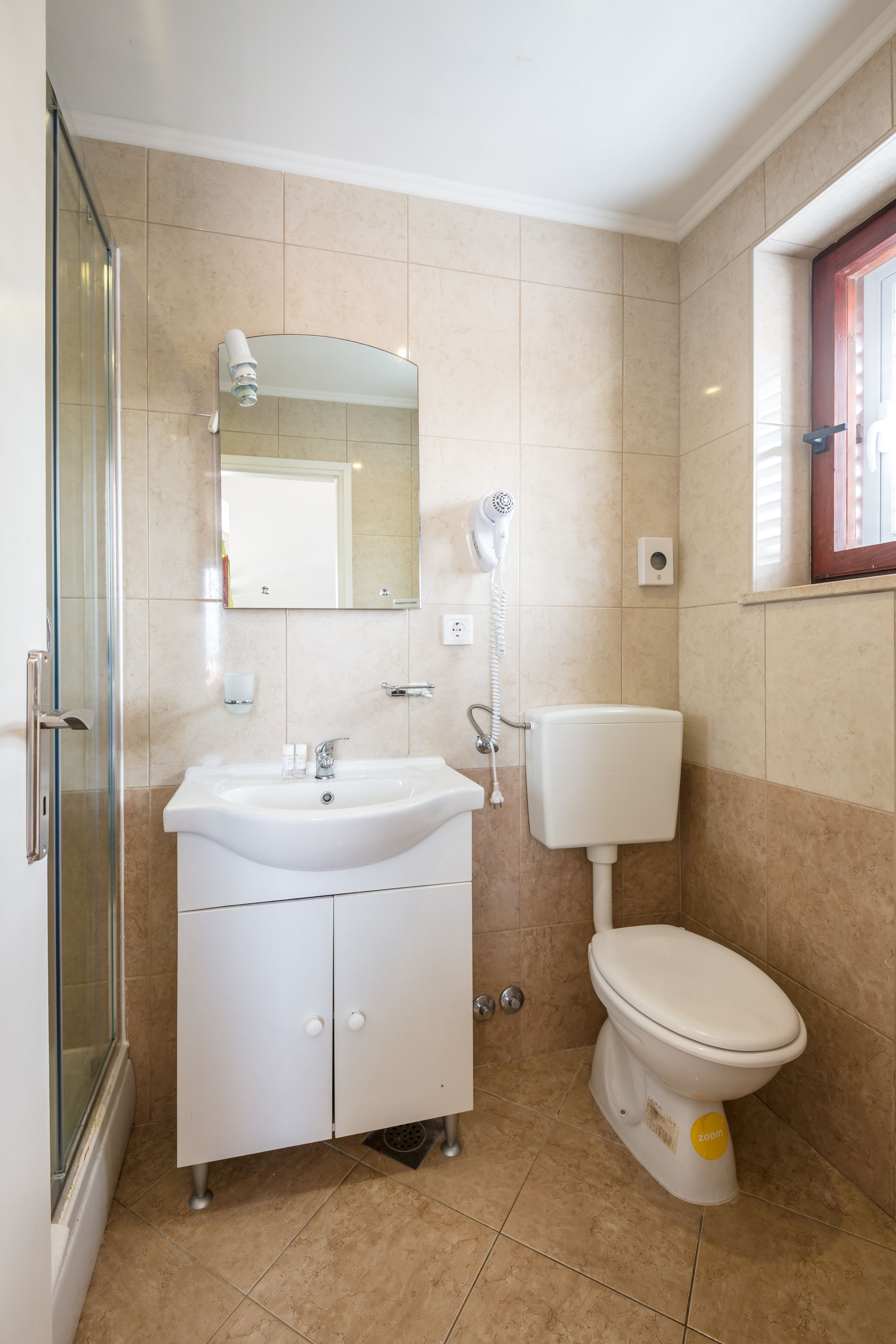 Un baño con ducha, lavabo, inodoro y espejo.