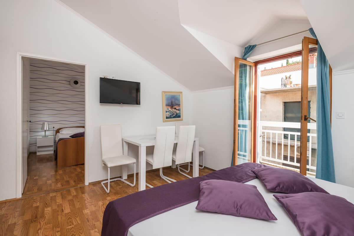 Une chambre avec un lit, un bureau, des chaises, une télévision et un balcon avec vue.