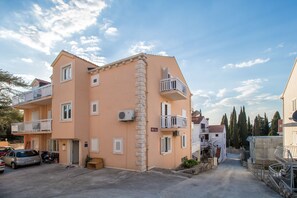 A two-story building with balconies, a car parked in front, and a clear sky. - Villa Voinić (Konavle)