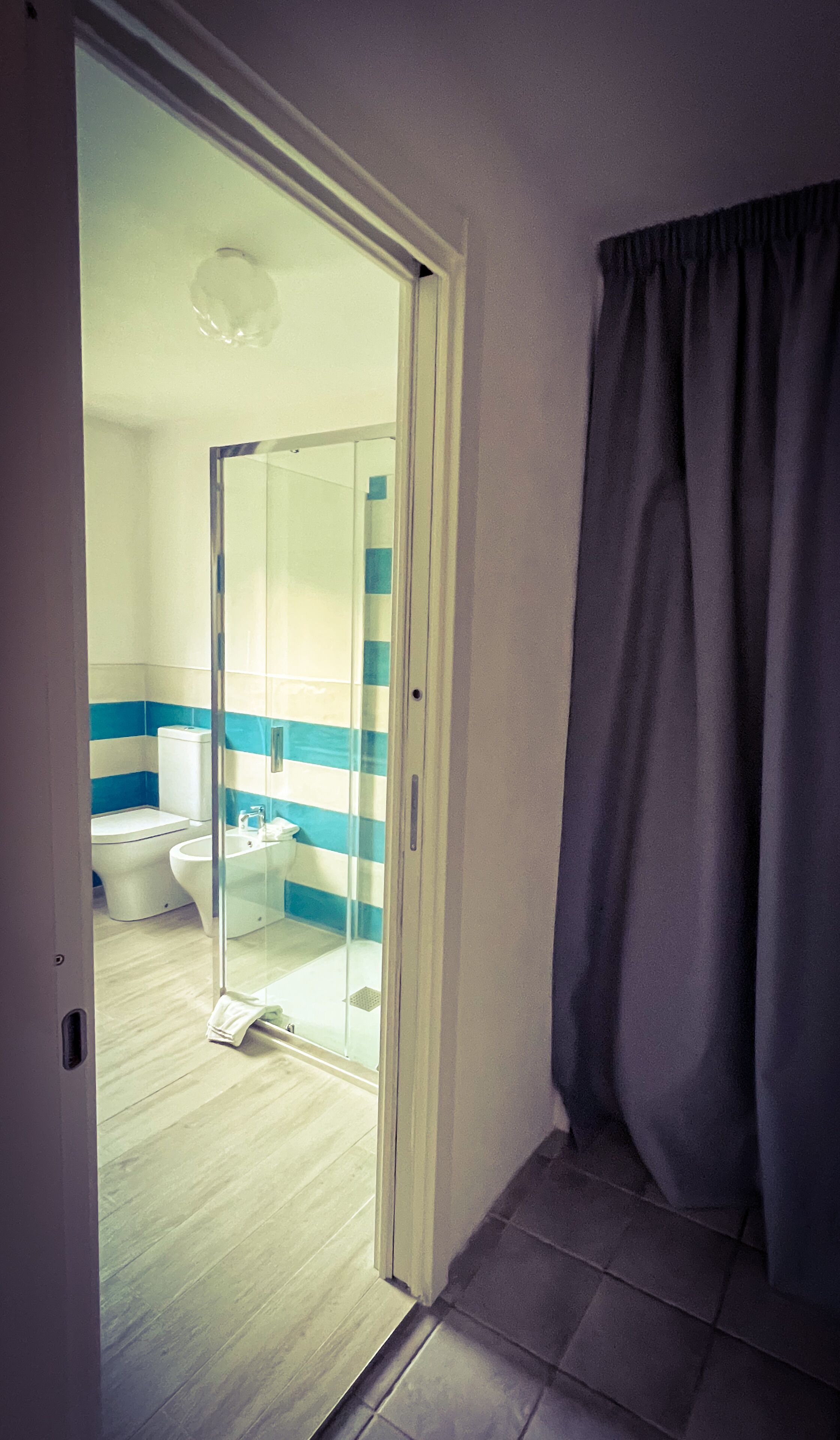 A bathroom with a glass shower enclosure, a toilet, and a sink.