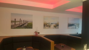 A room with three paintings on the wall, a small potted plant, and a seating area with a table and chairs. - Hotel Royal Santana (Altenahr)
