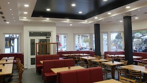 A restaurant with booths and tables, large windows, and a modern ceiling design. - Hotel Royal Santana (Altenahr)