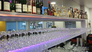 A bar area with shelves of wine bottles and a bar counter with numerous glasses and bottles. - Hotel Royal Santana (Altenahr)