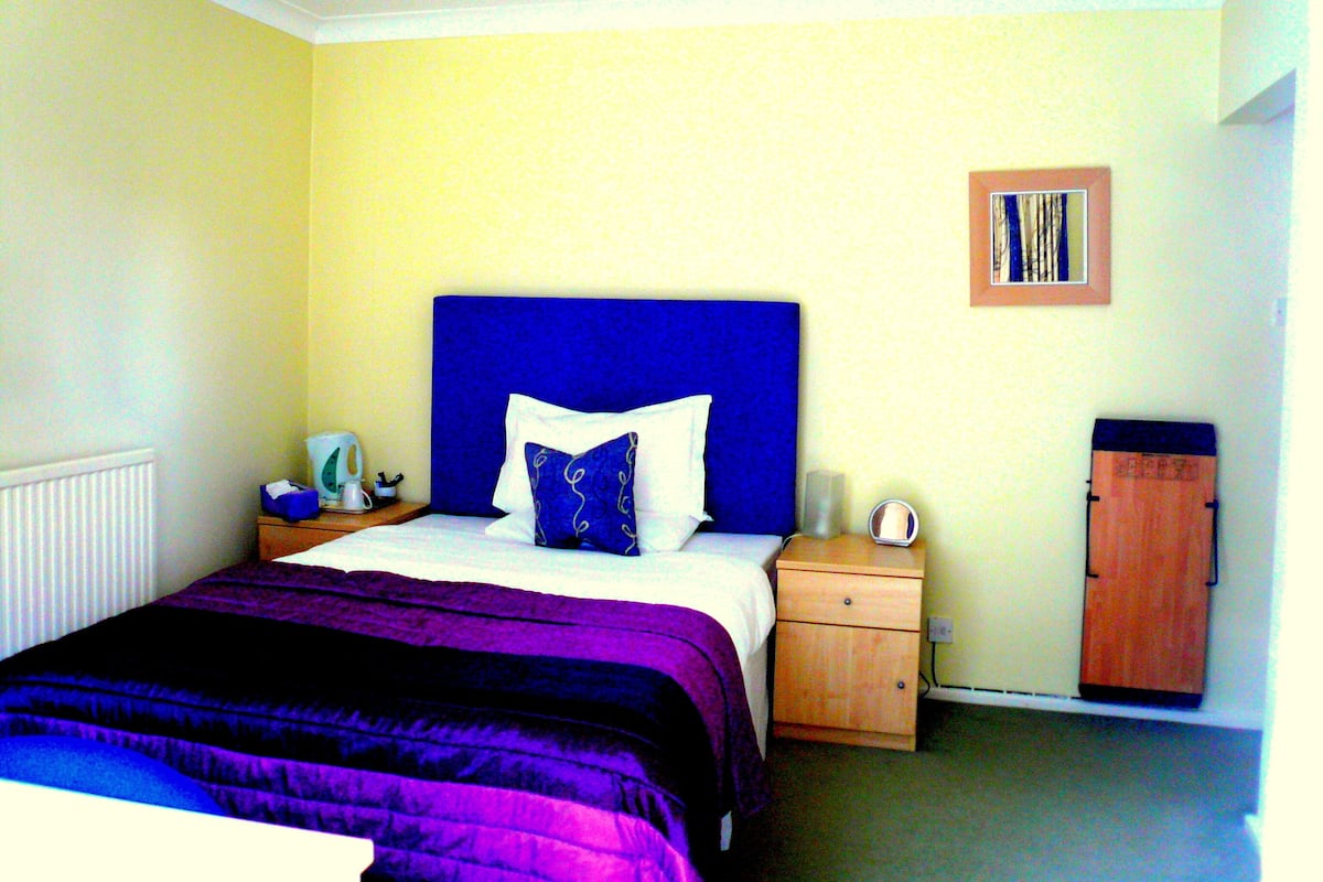 A hotel room with a bed, a nightstand, a wardrobe, and a painting on the wall.