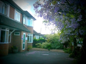 A residential building with a brick facade, a front door, and a driveway leading to a parking area. - Malvern House (High Wycombe)