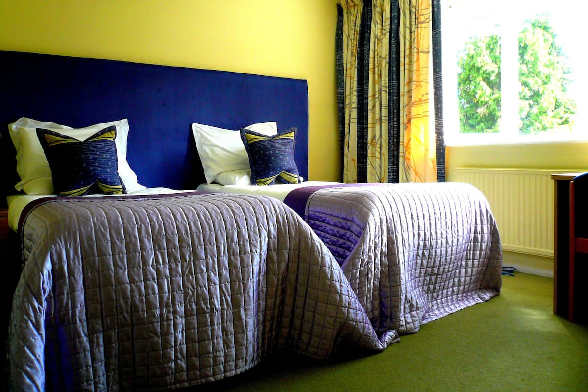 A double bed with a headboard, two pillows, and a quilted bedspread.