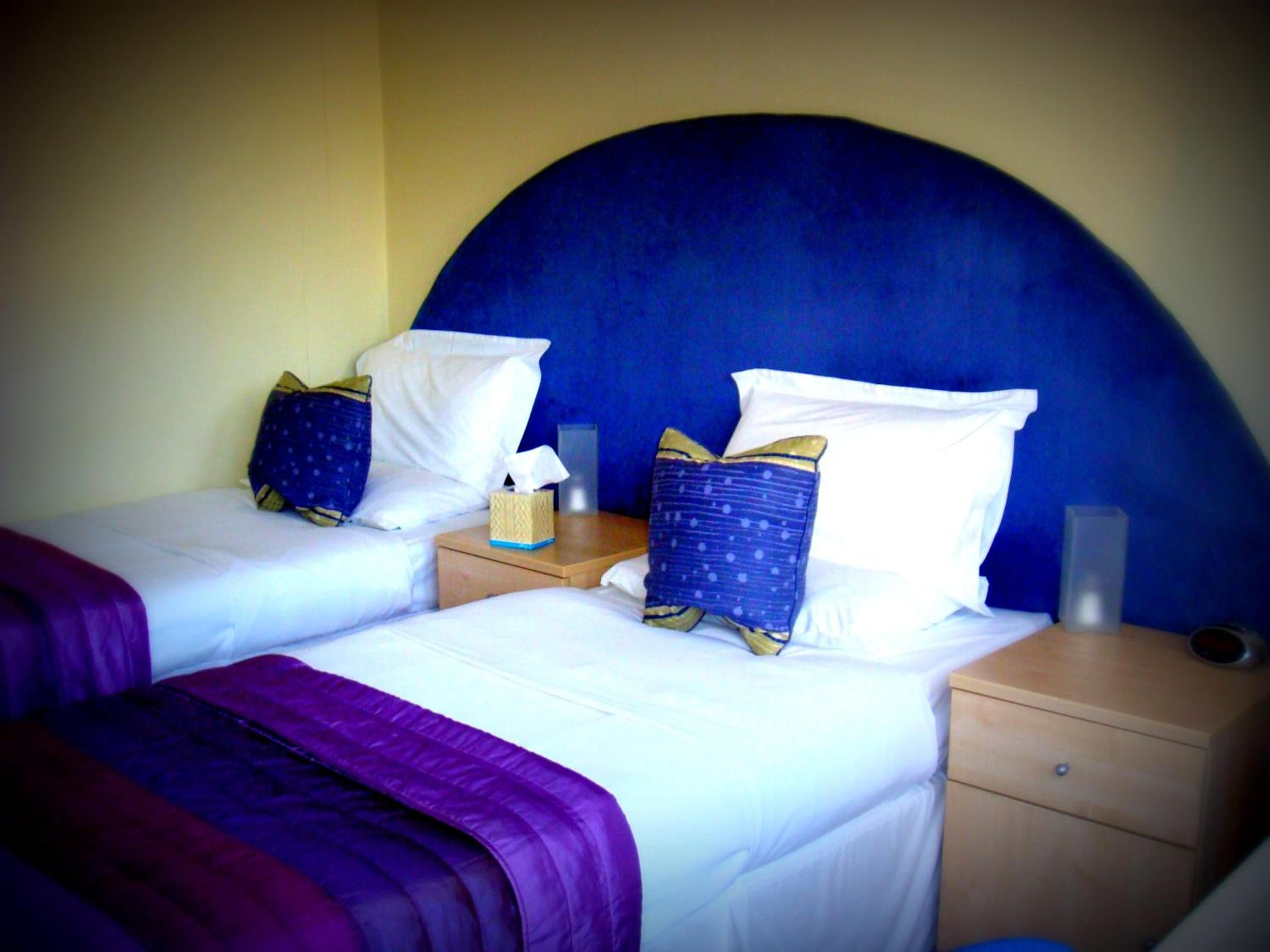 Two twin beds with headboards, a bedside table with a tissue box, and a nightstand with a lamp.