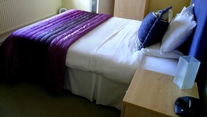 Ein Schlafzimmer mit Bett, Nachttisch und Fenster.