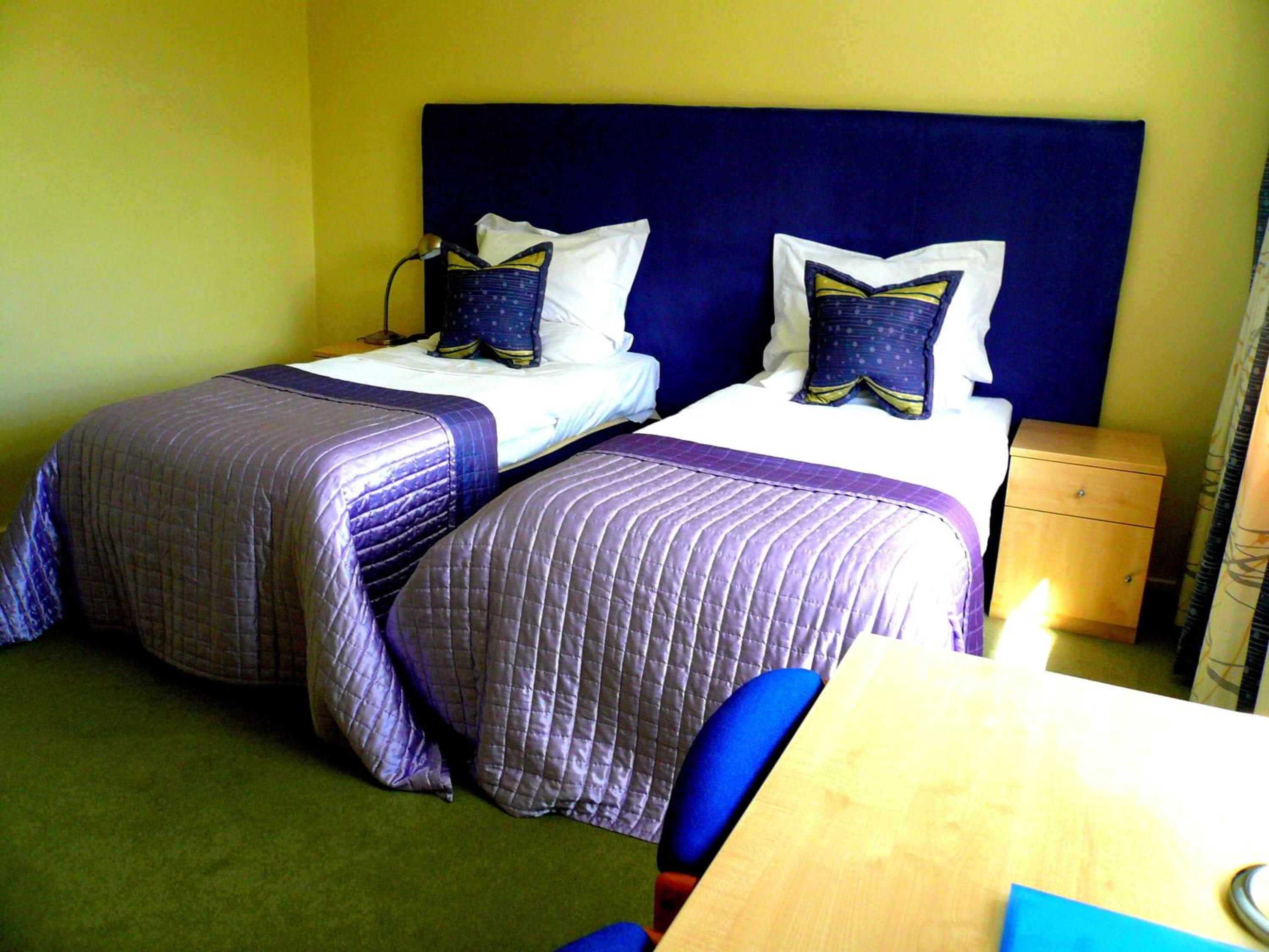 A hotel room with two beds, a desk, and a nightstand.