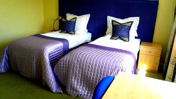 A hotel room with two beds, a desk, and a nightstand.