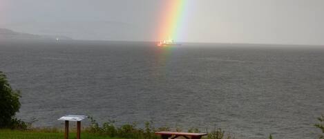 Une table de pique-nique près d’un plan d’eau, avec un arc-en-ciel en arrière-plan.