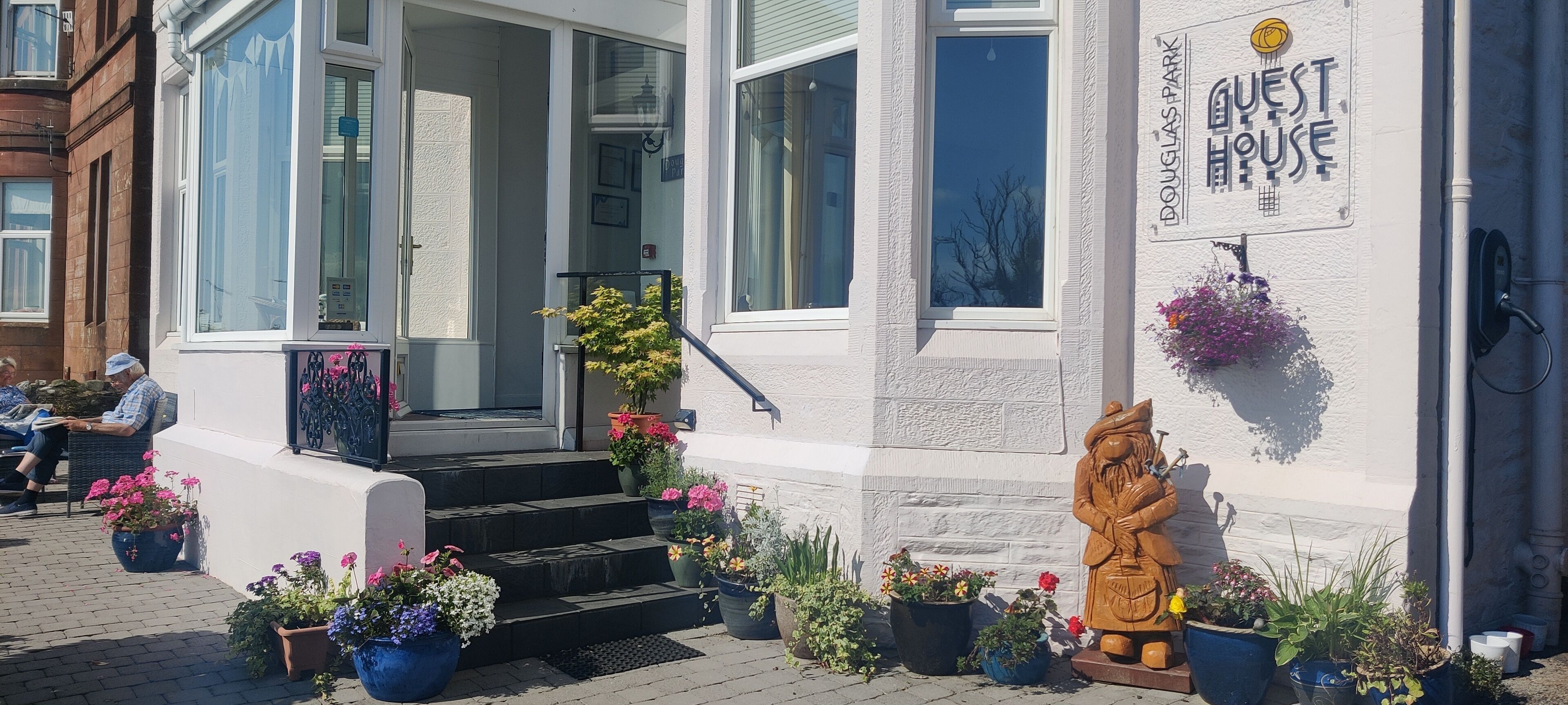 A building with a sign reading 'GUEST HOUSE' and a wooden statue on the sidewalk.