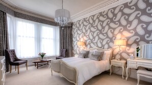 A spacious bedroom with a large bed, two bedside tables, a dresser, and a chair. - Douglas Park Guest House (Dunoon)