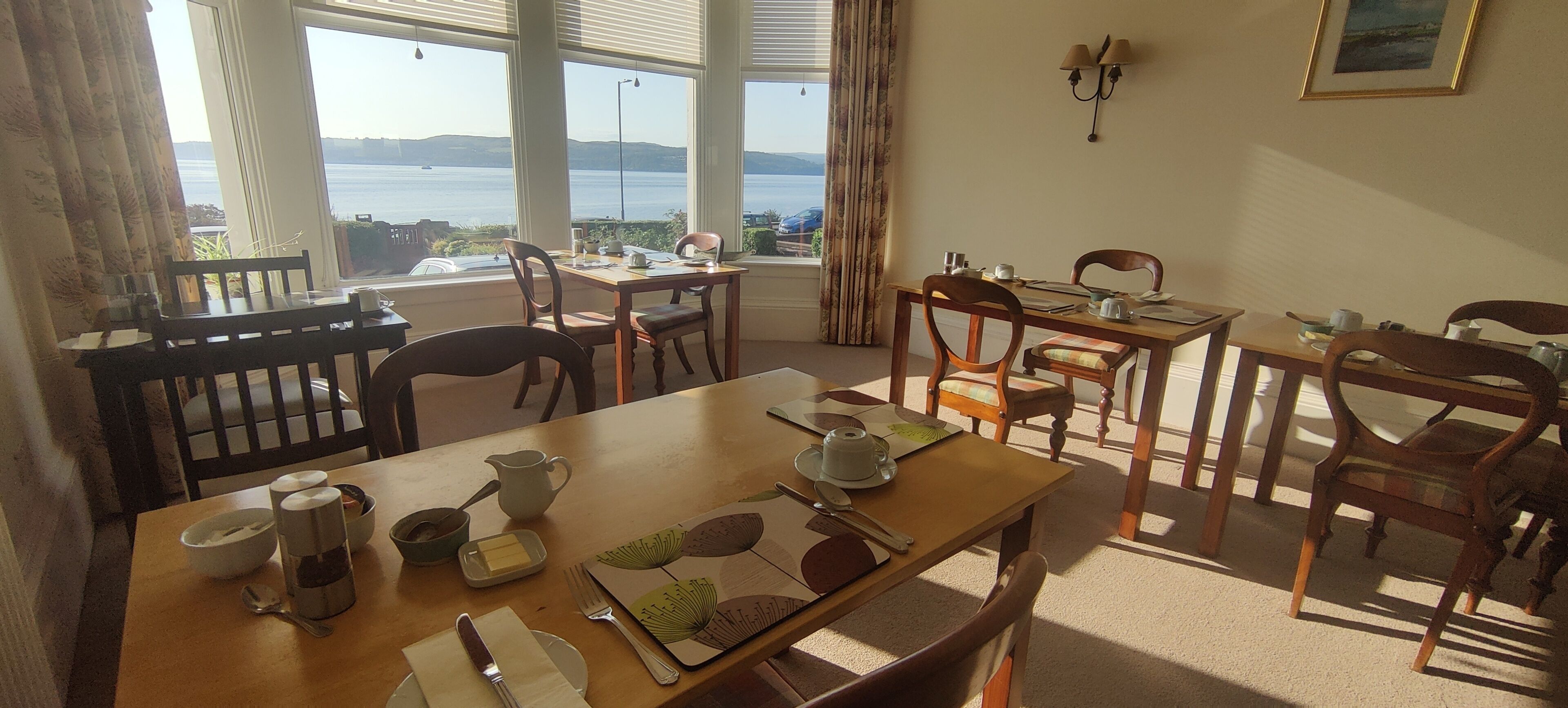 Comedor con vistas al mar, mobiliario de madera y una mesa dispuesta para dos.