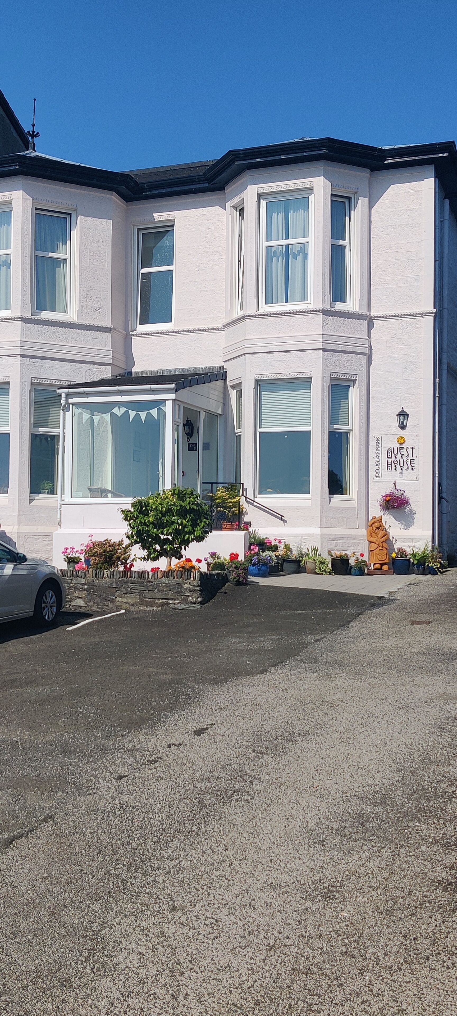 A two-story building with a white facade, large windows, and a sign that reads 'GUEST HOUSE'.