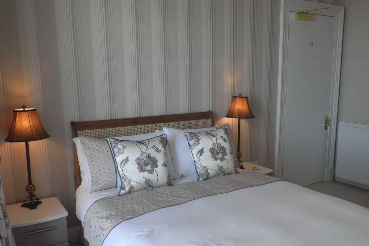 A neatly made bed with floral pillows, two bedside lamps, and a wooden headboard.