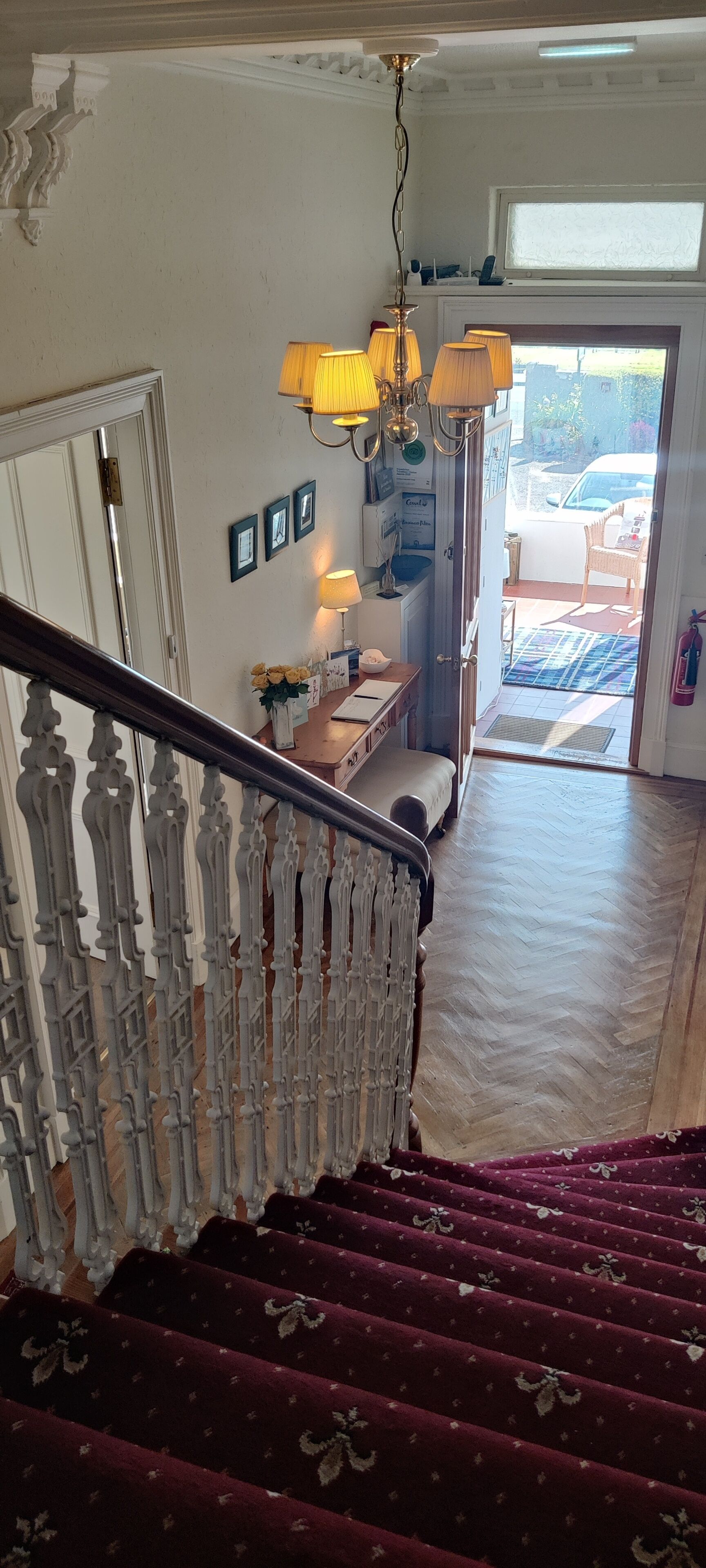 A staircase with ornate balusters leading to a landing with a bench and a lamp.
