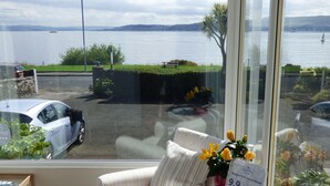A room with a view of a lake, a parked car, and a sign indicating a guest house rate of 9.9. - Douglas Park Guest House (Dunoon)