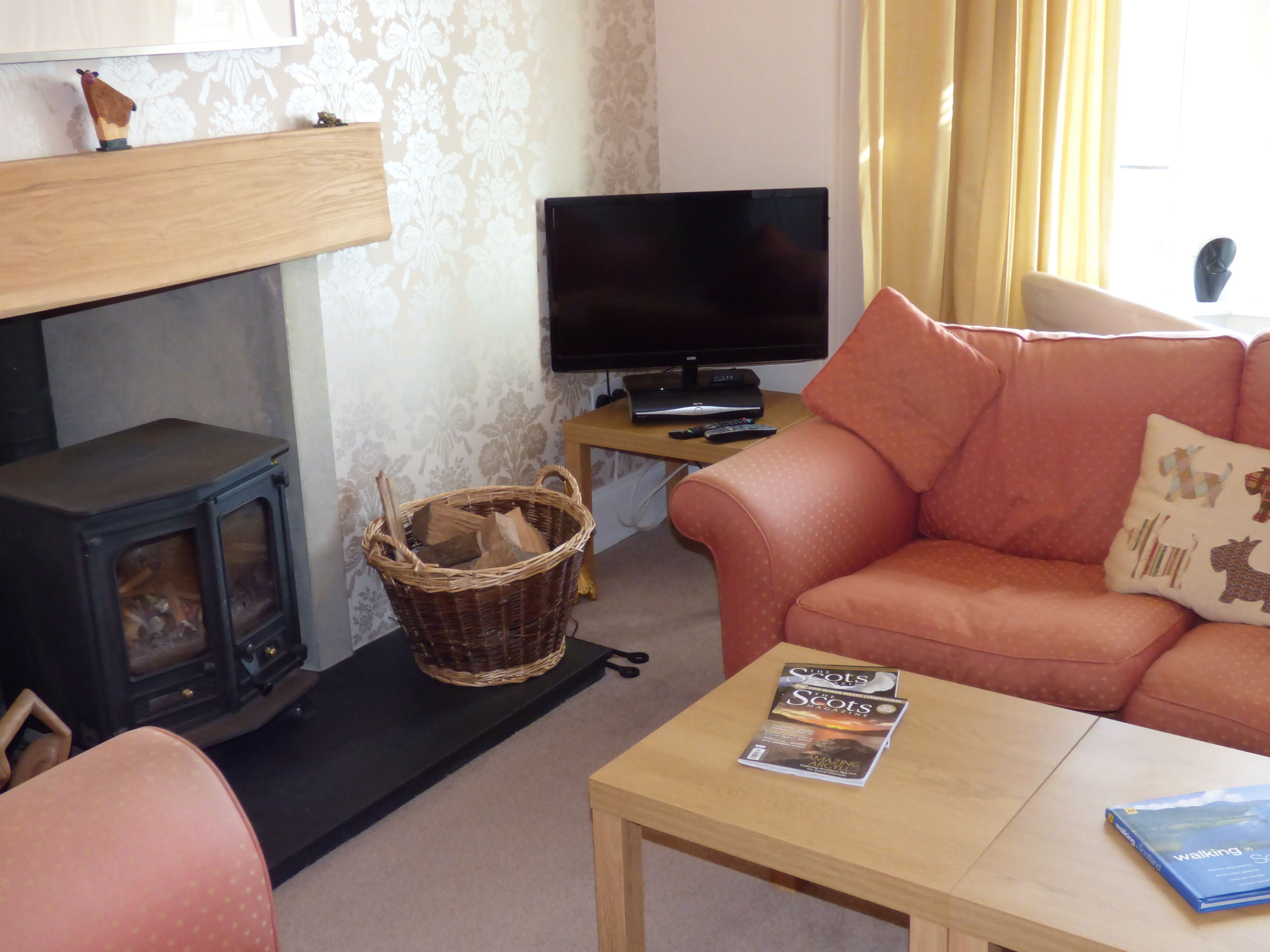 A cozy living room with a fireplace, a television, a sofa, and a table with magazines.